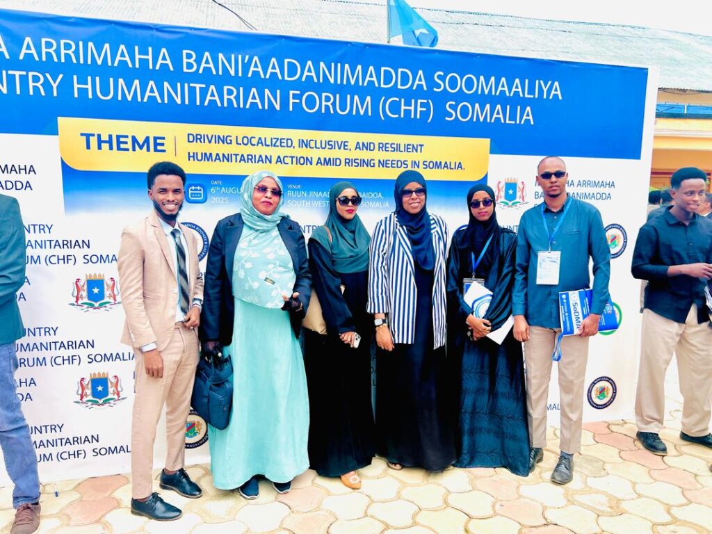 Participants standing in front of the Country Humanitarian Forum 2025 banner in Baidoa